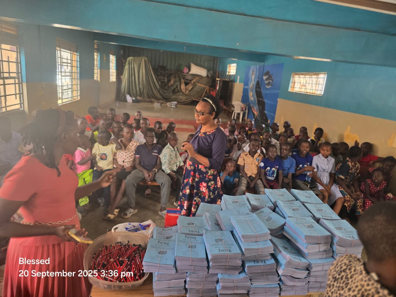 A teacher distributing exercise books and pens to children