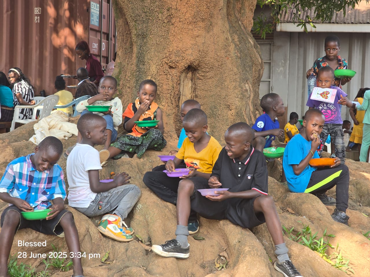 Children eating from coloured bowls under a tree