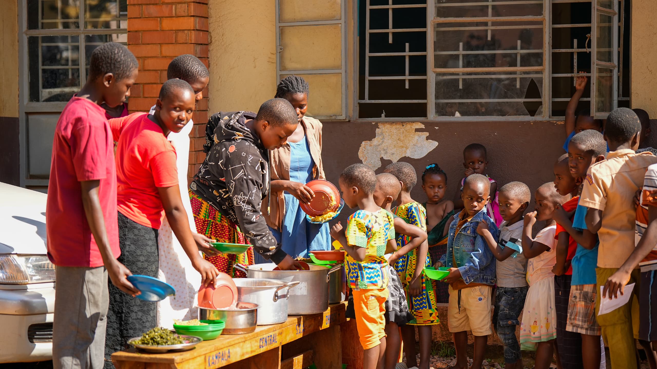 Volunteers serving hot meals to children in Kivulu