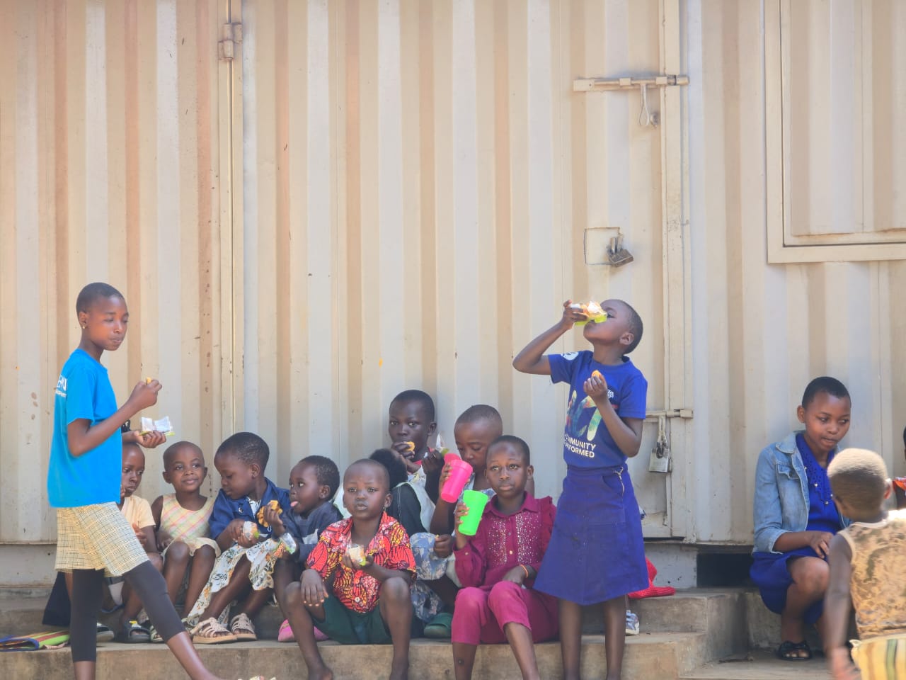 Children eating snacks on container steps